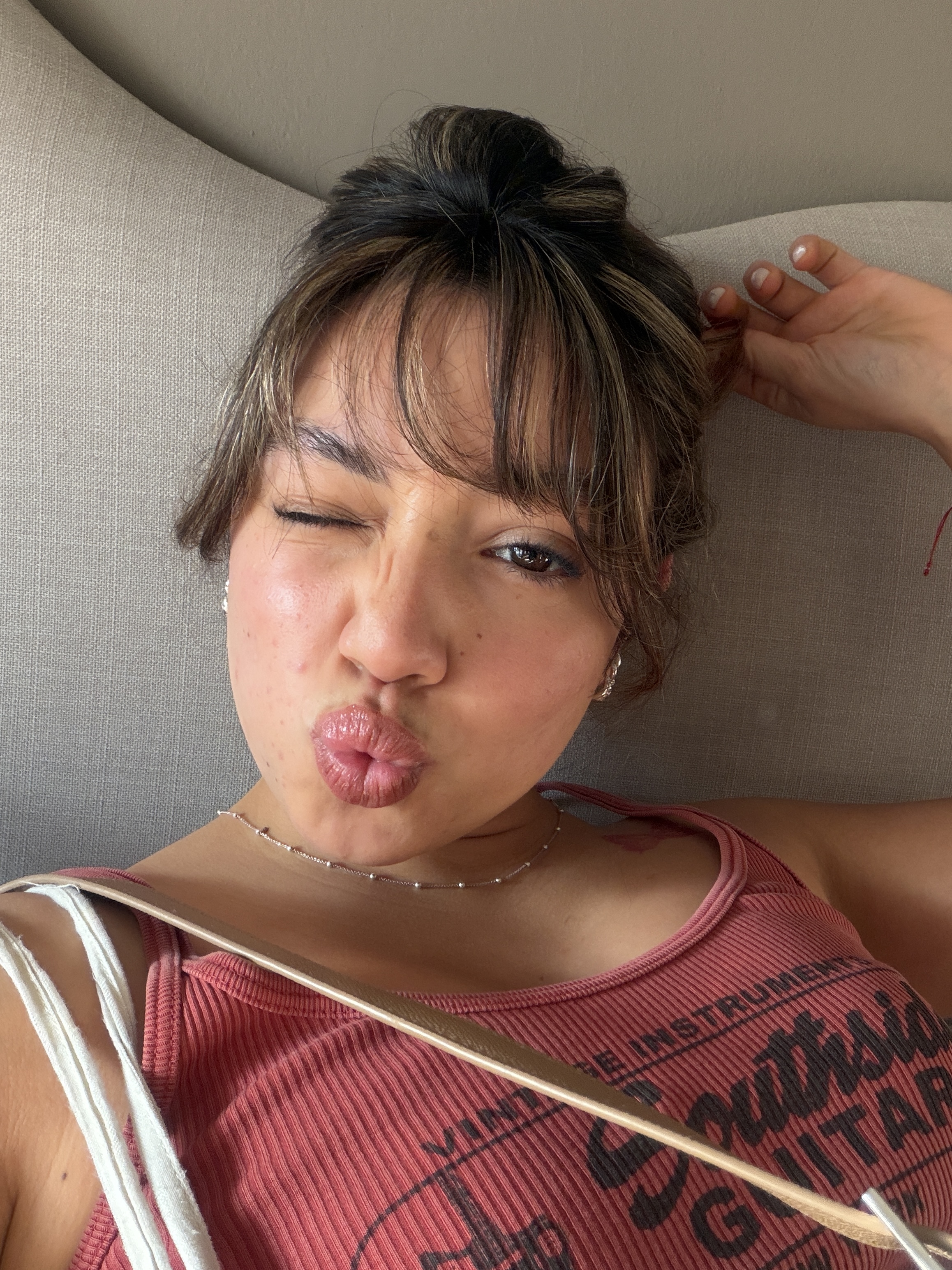 Sofia making a playful kissy face and winking at the camera while lounging on a couch